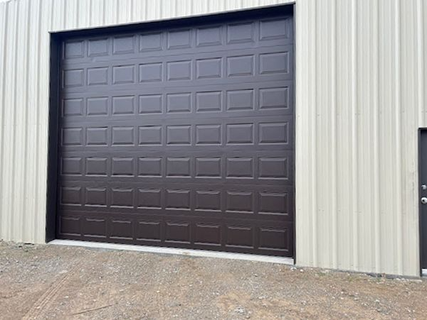 Dark brown roll-up garage door on a beige metal building exterior.