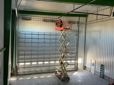 Scissor lift raised inside an industrial garage with a closed roll-up door