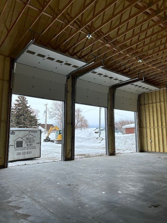 Empty industrial warehouse with open garage doors, snowy outdoors visible.