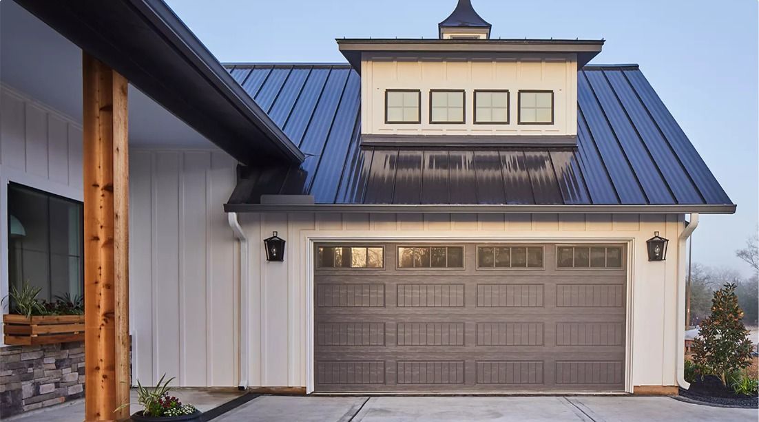 White house exterior with blue metal roof and a gray garage door at dusk