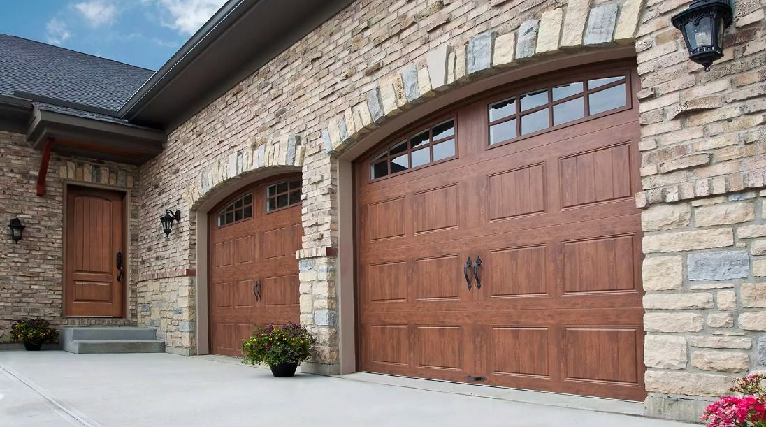 Stone house exterior with three wooden garage doors and a paved driveway