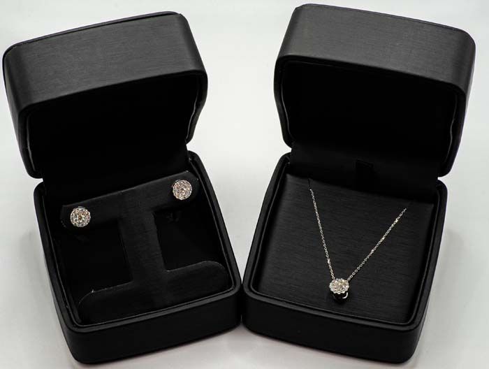 Two black jewelry boxes open, showing a silver necklace and matching earrings on white background