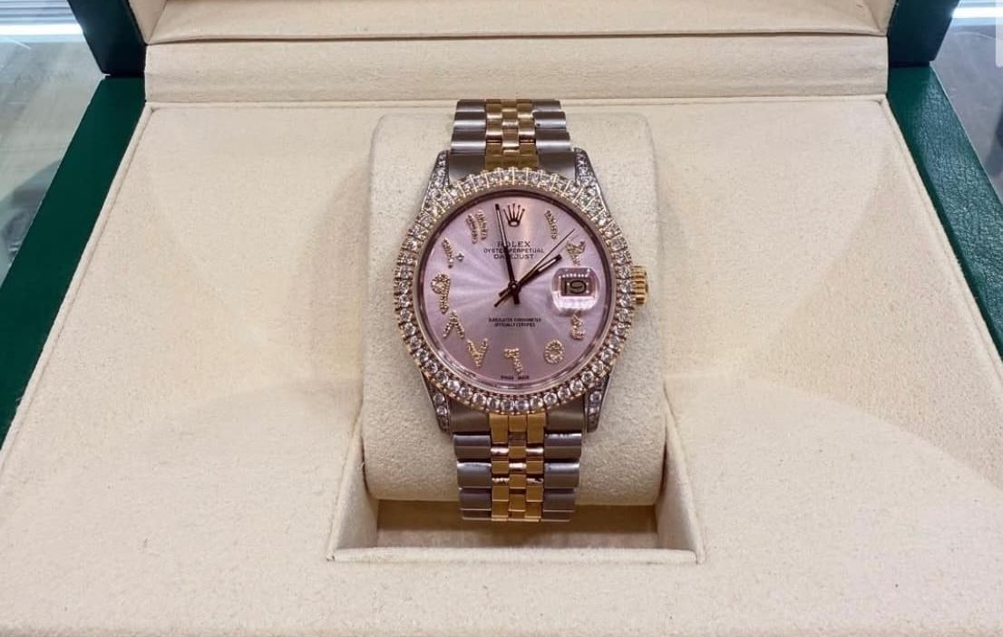 Two-tone wristwatch with a pink face, displayed in an open presentation box.