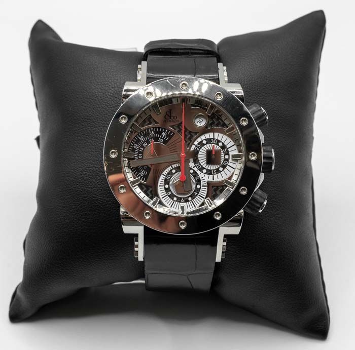 Black wristwatch with a silver skeleton dial displayed on a black cushion