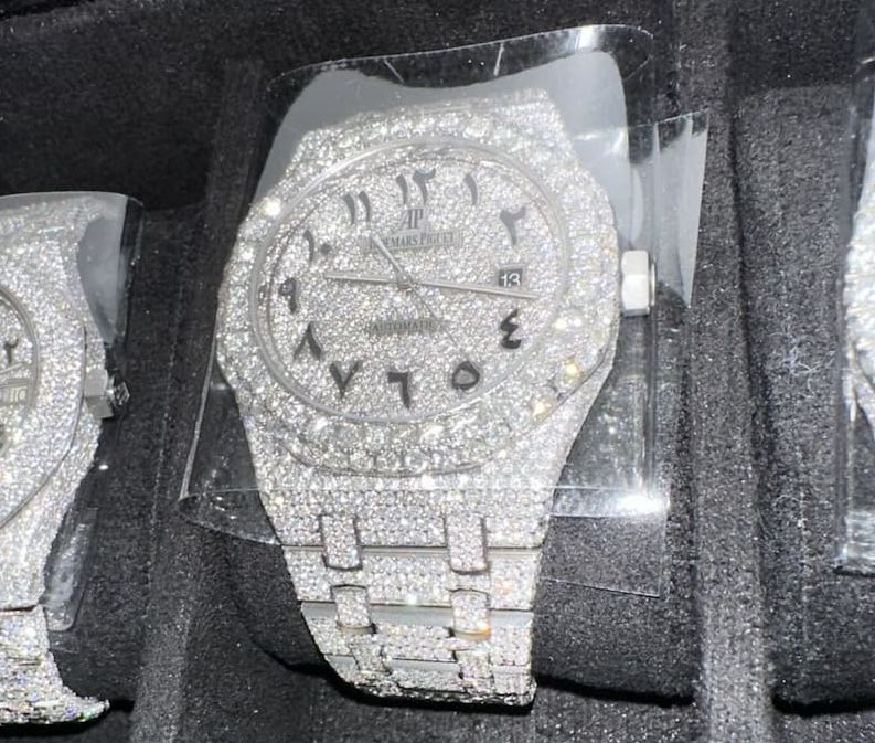 Diamond-encrusted silver wristwatch displayed in a black velvet case.