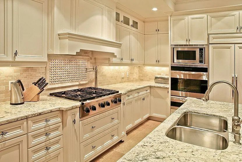 Cream-colored kitchen with granite countertops, stainless steel appliances, and a stovetop range.