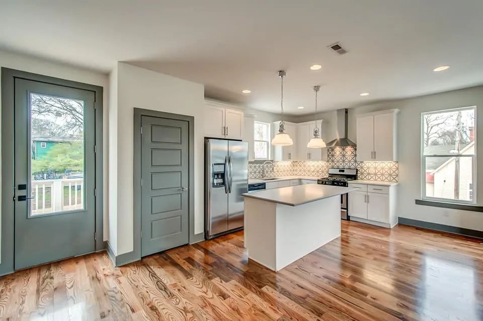 Modern kitchen with white cabinets, stainless steel appliances, and hardwood floors.