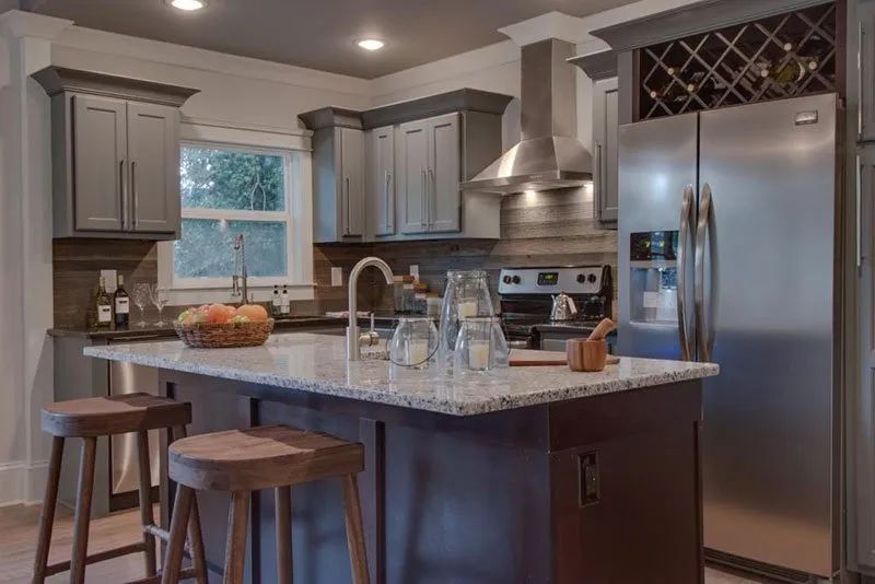 Modern kitchen with gray cabinets, granite countertops, and stainless steel appliances.