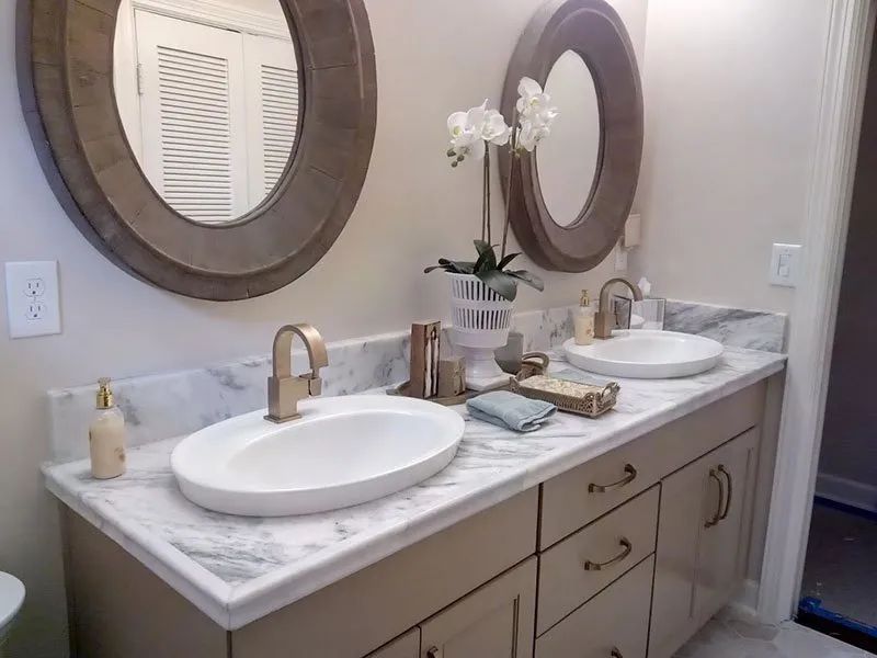 Bathroom vanity with two sinks, oval mirrors, gold faucets, and orchid.