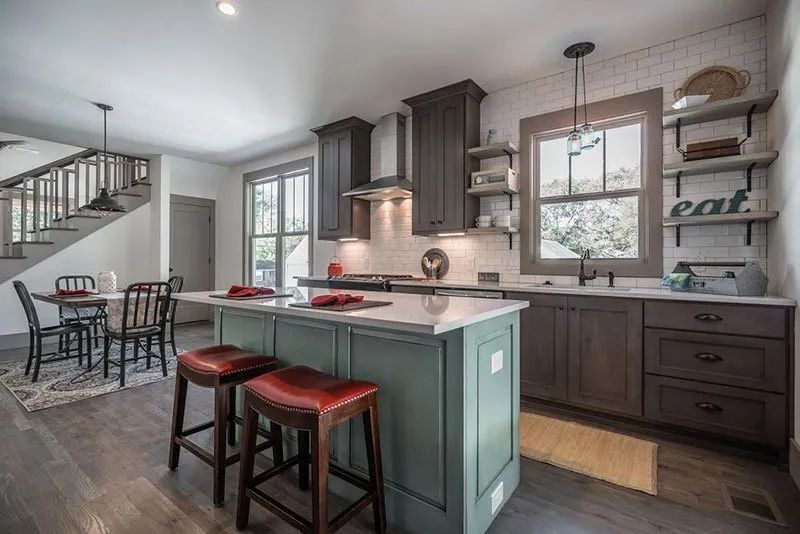 Modern kitchen with island and bar stools, dark cabinets, and exposed shelves.