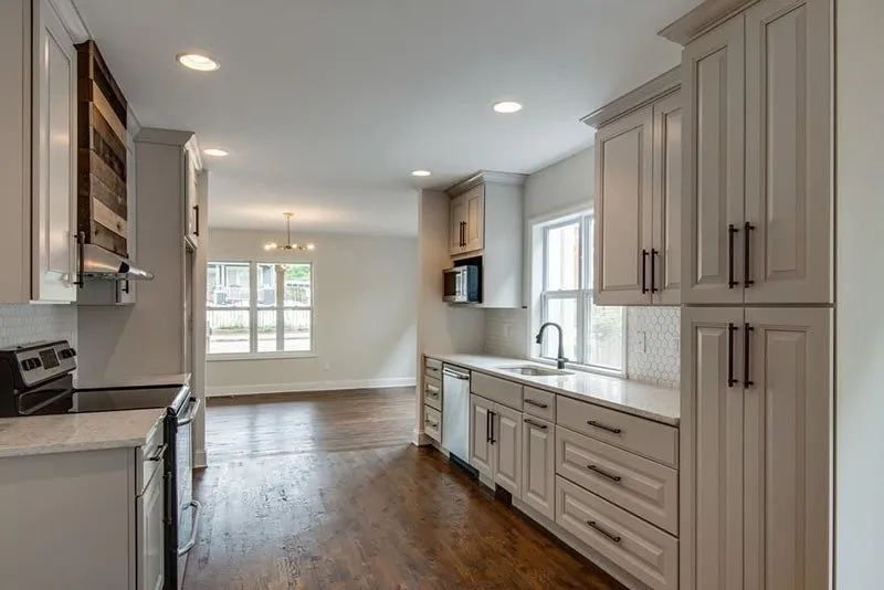 Modern kitchen with light gray cabinets, white countertops, and dark wood floors.