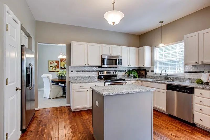 Kitchen with white cabinets, stainless steel appliances, granite countertops, and wood floor.