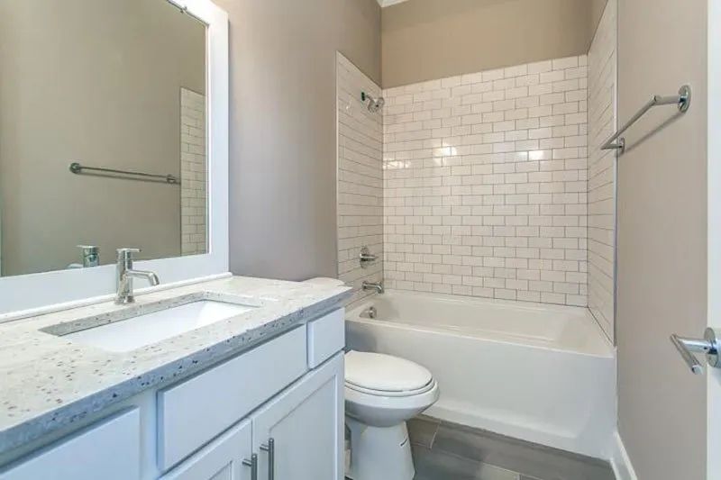 White bathroom with a bathtub, toilet, vanity, and subway tile walls.