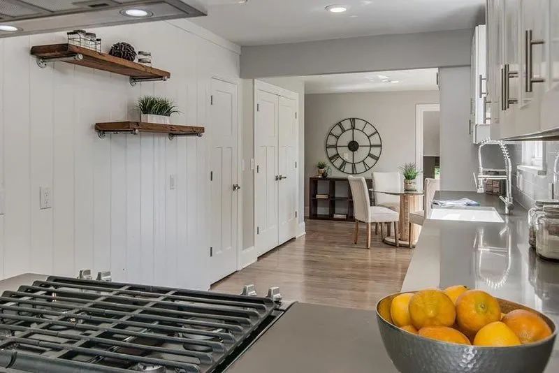 Modern kitchen with white cabinets, gray countertops, and a view into a dining room.