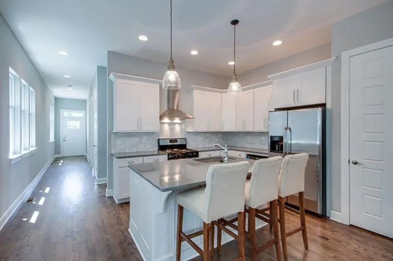Modern kitchen with white cabinets, stainless steel appliances, and island with three bar stools.
