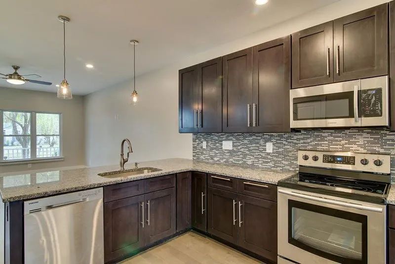 Modern kitchen with dark brown cabinets, stainless steel appliances, and granite countertops.