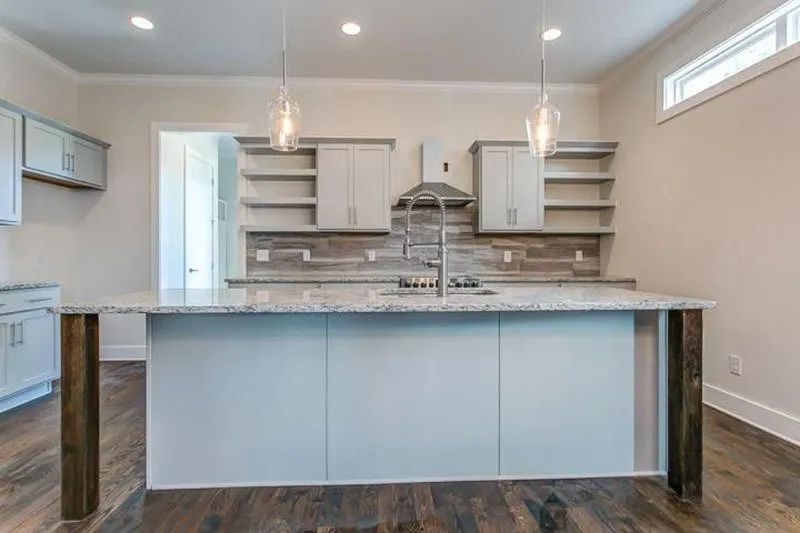Modern kitchen with a light blue island, white cabinets, and wooden accents.