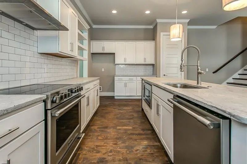 Modern kitchen with white cabinets, stainless steel appliances, and island with sink.