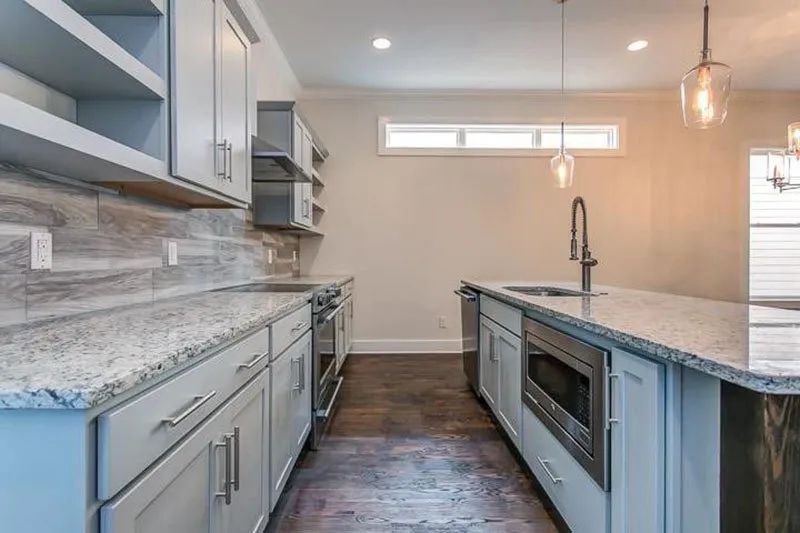 Modern kitchen with gray cabinets, granite countertops, and stainless steel appliances.