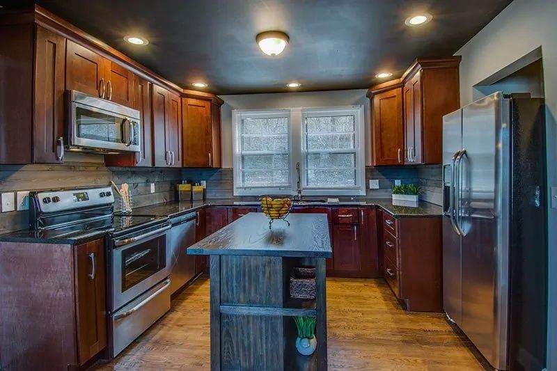 Kitchen with dark wood cabinets, stainless steel appliances, and a central island.