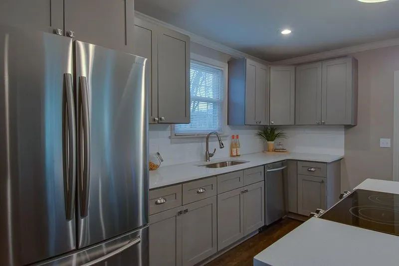 Gray kitchen with stainless steel appliances, light countertops, and cabinets.