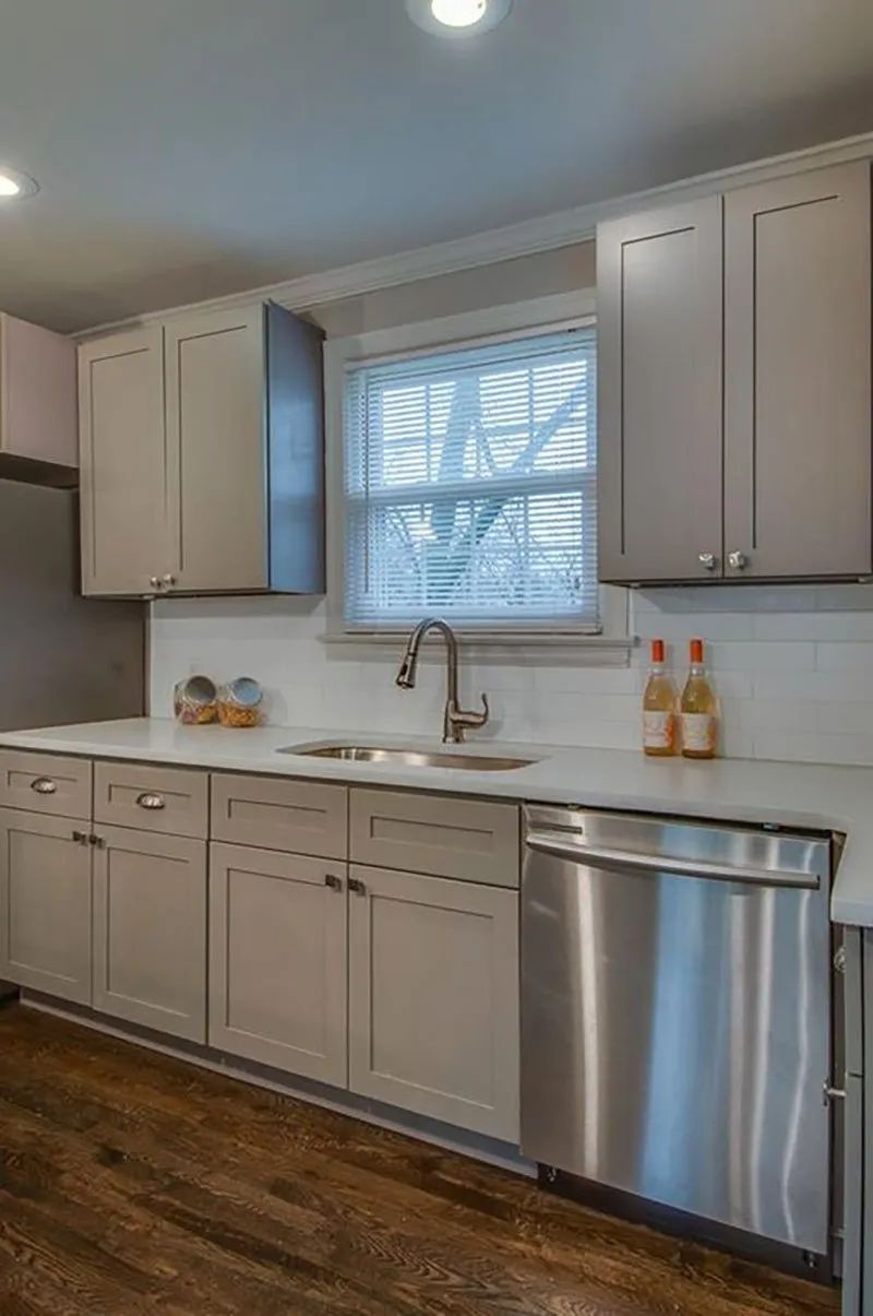 Gray kitchen with stainless steel appliances, white countertop, and wood floors.