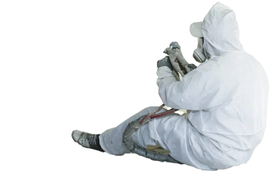 Person in a white protective suit sitting, holding a spray gun.