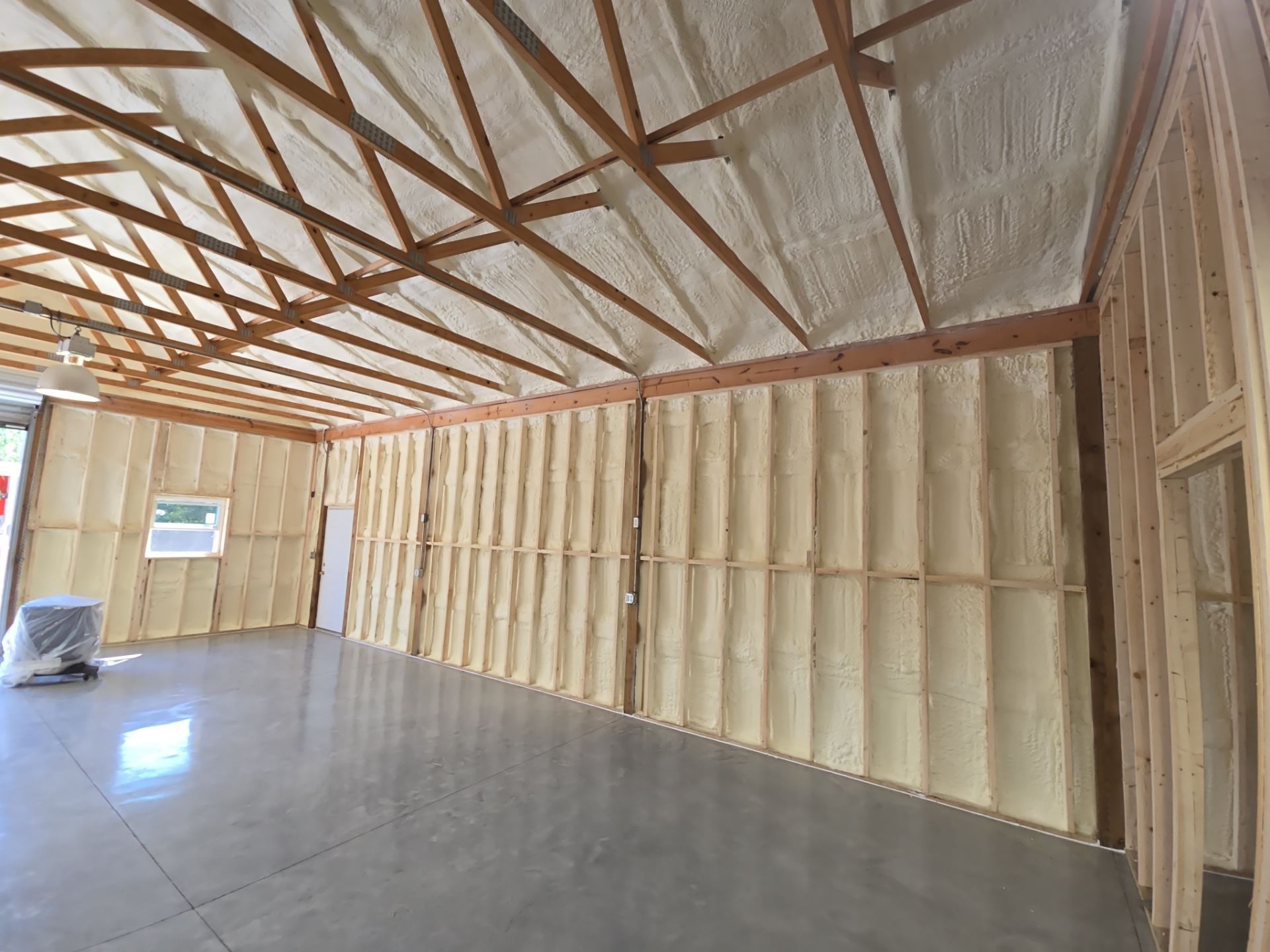 Interior view of a building's wooden frame, insulation, and concrete floor.