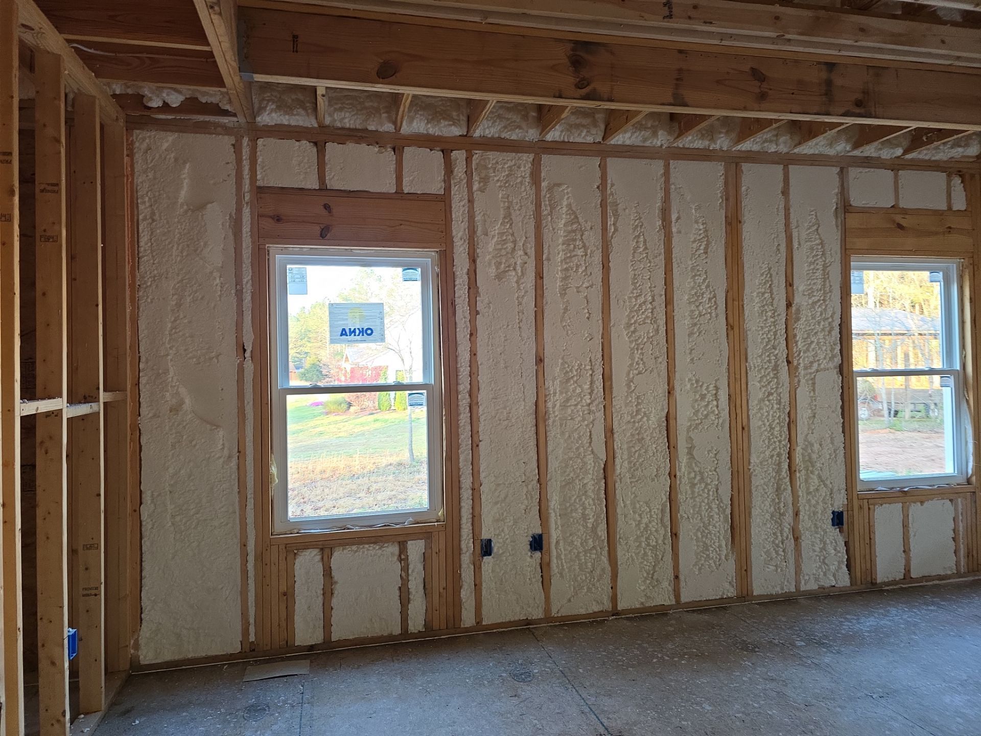 Interior wall framing with spray foam insulation between studs, two windows.