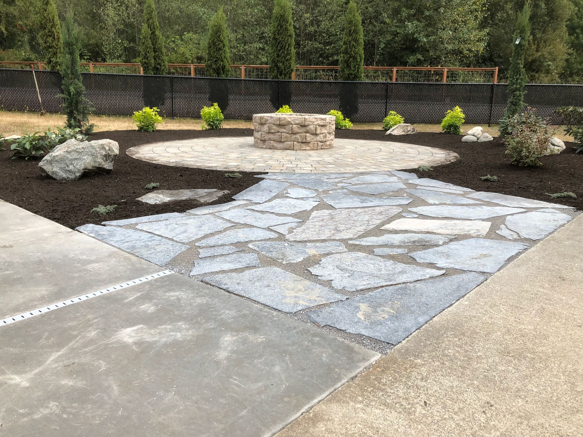 A stone patio with a fire pit in the middle of it.
