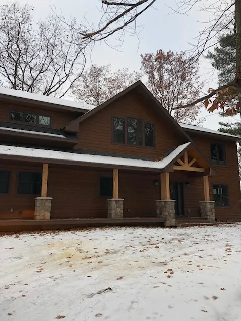 a large brown house with snow on the ground in front of it