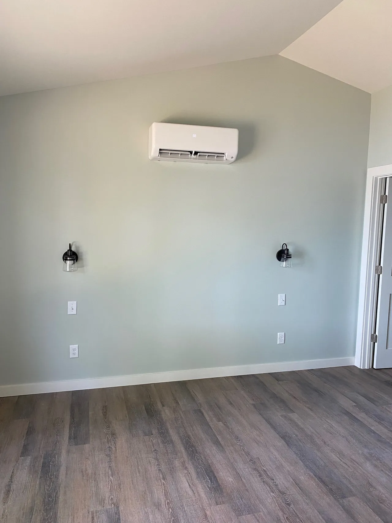 an empty room with hardwood floors and a wall mounted air conditioner