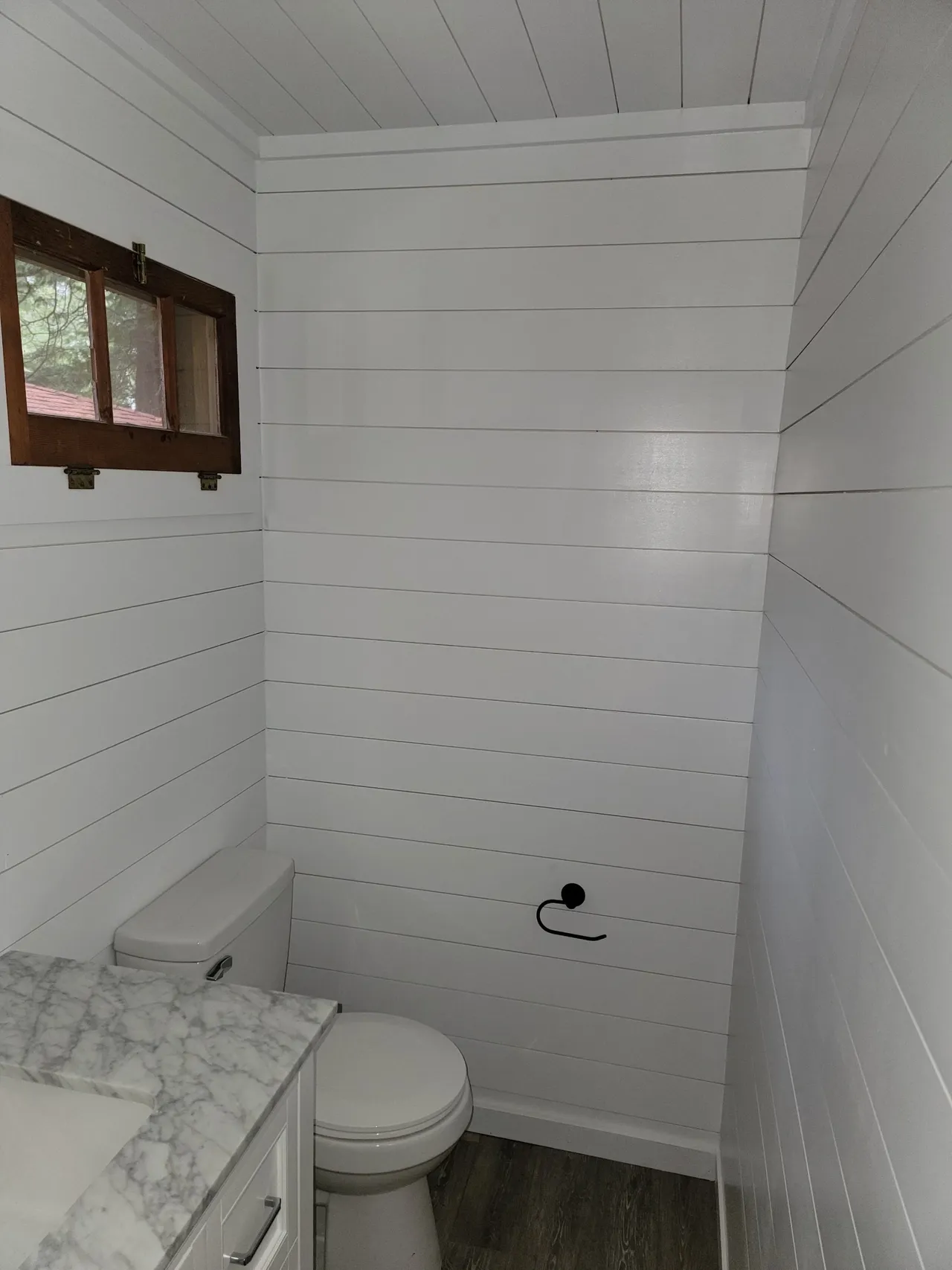 a bathroom with a toilet , sink and window