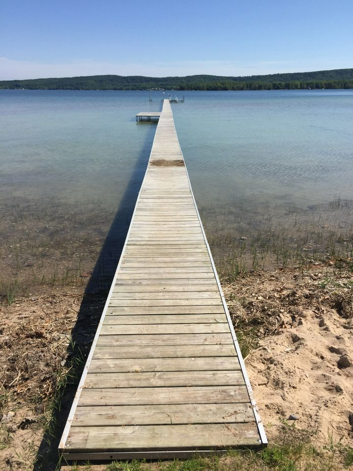 a long wooden dock leading into a lake on a sunny day