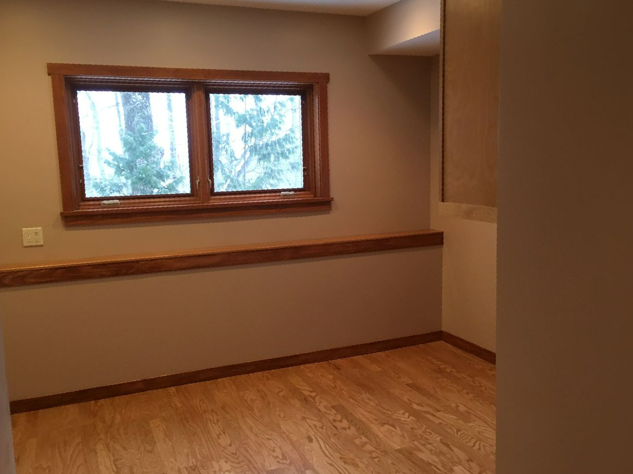 an empty room with hardwood floors and two windows
