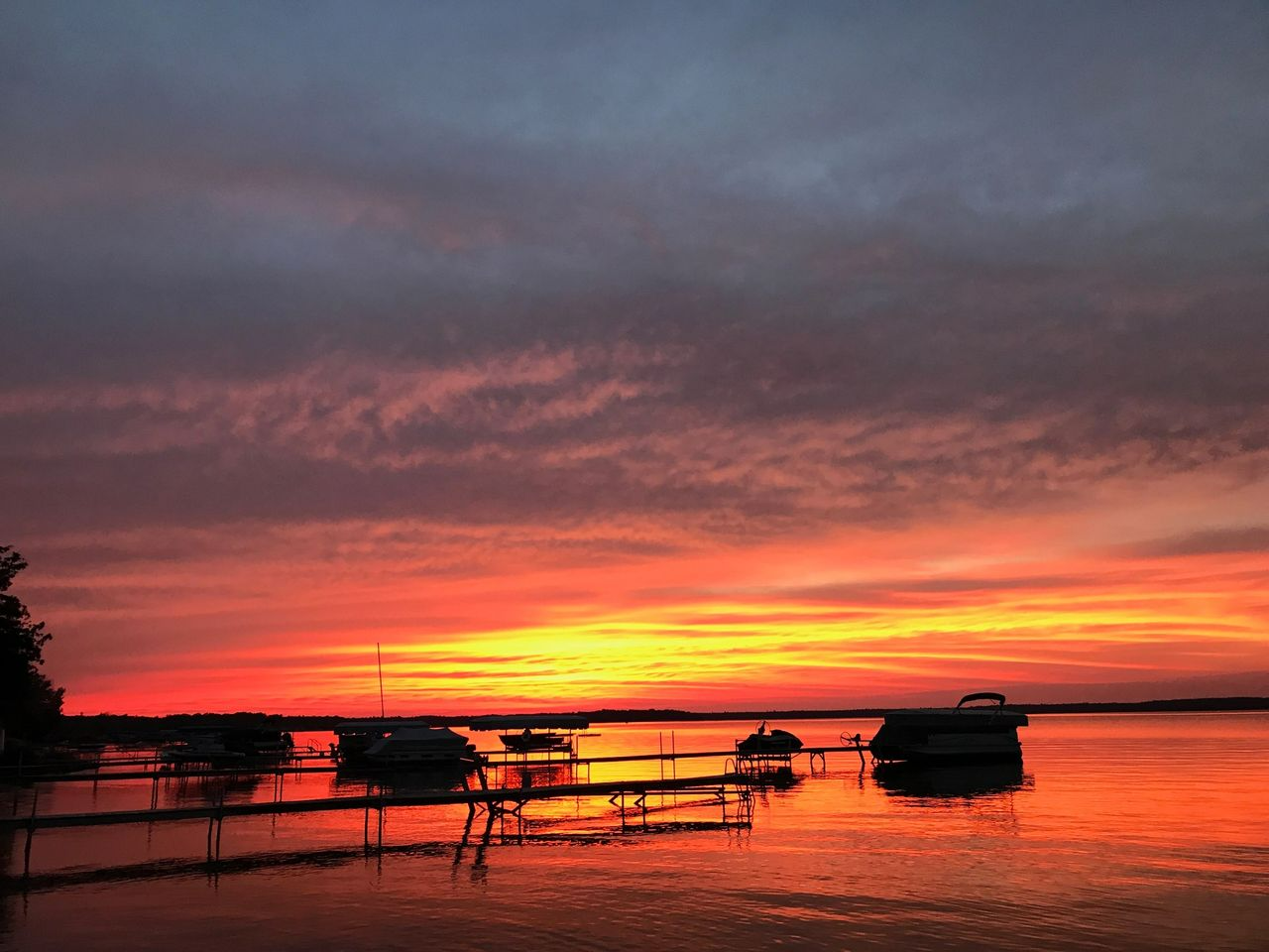 a sunset over a lake with boats docked in the water