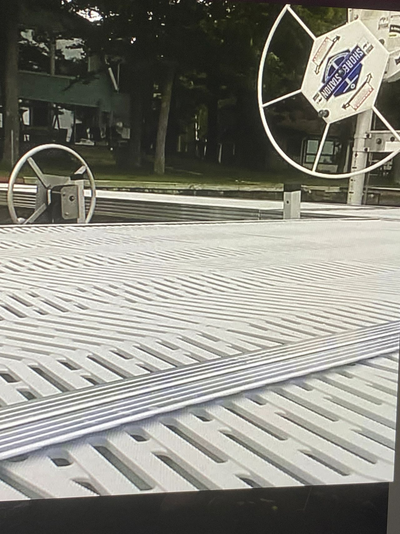 a picture of a steering wheel on a dock with trees in the background