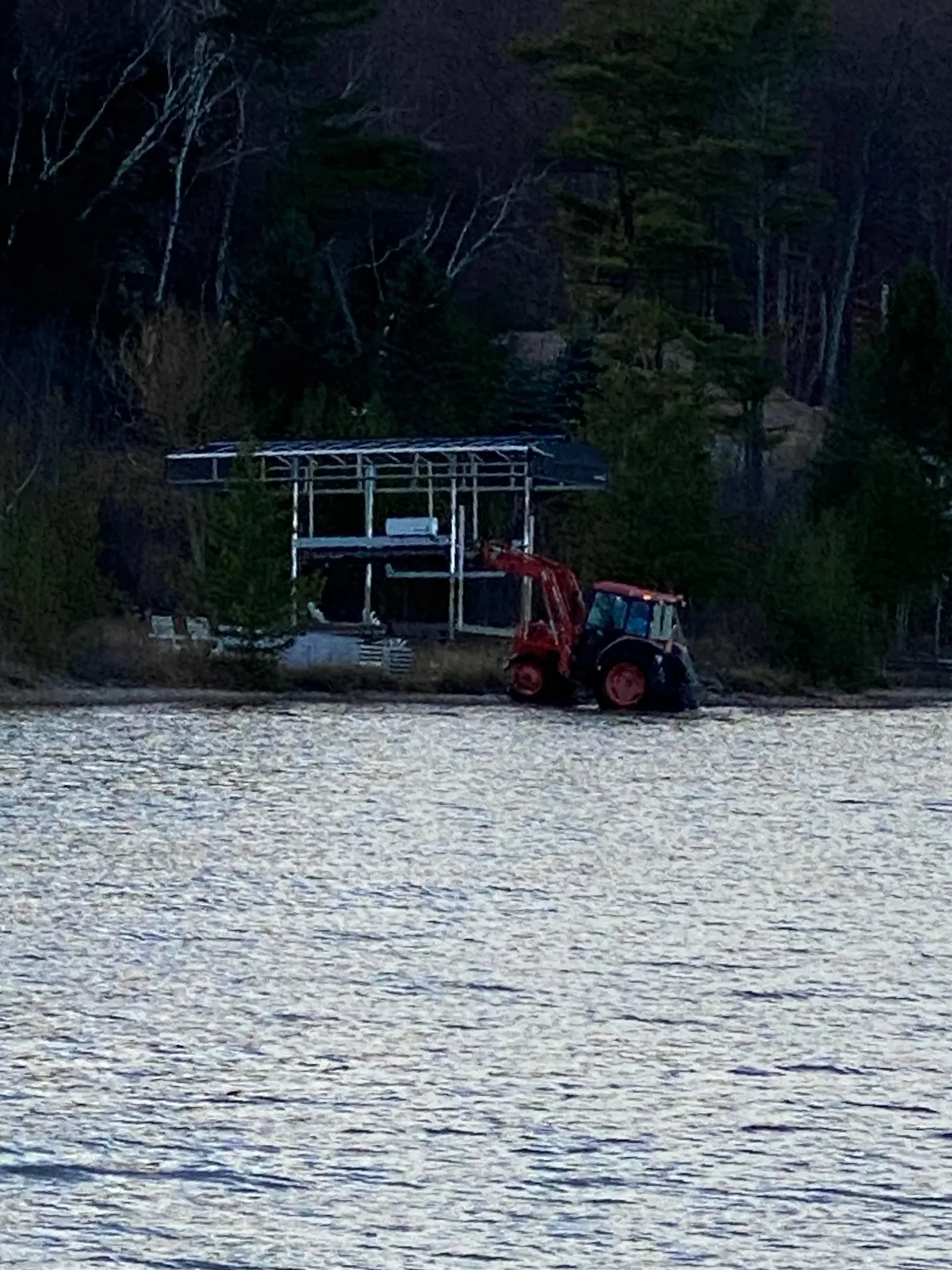 a tractor is parked on the shore of a lake