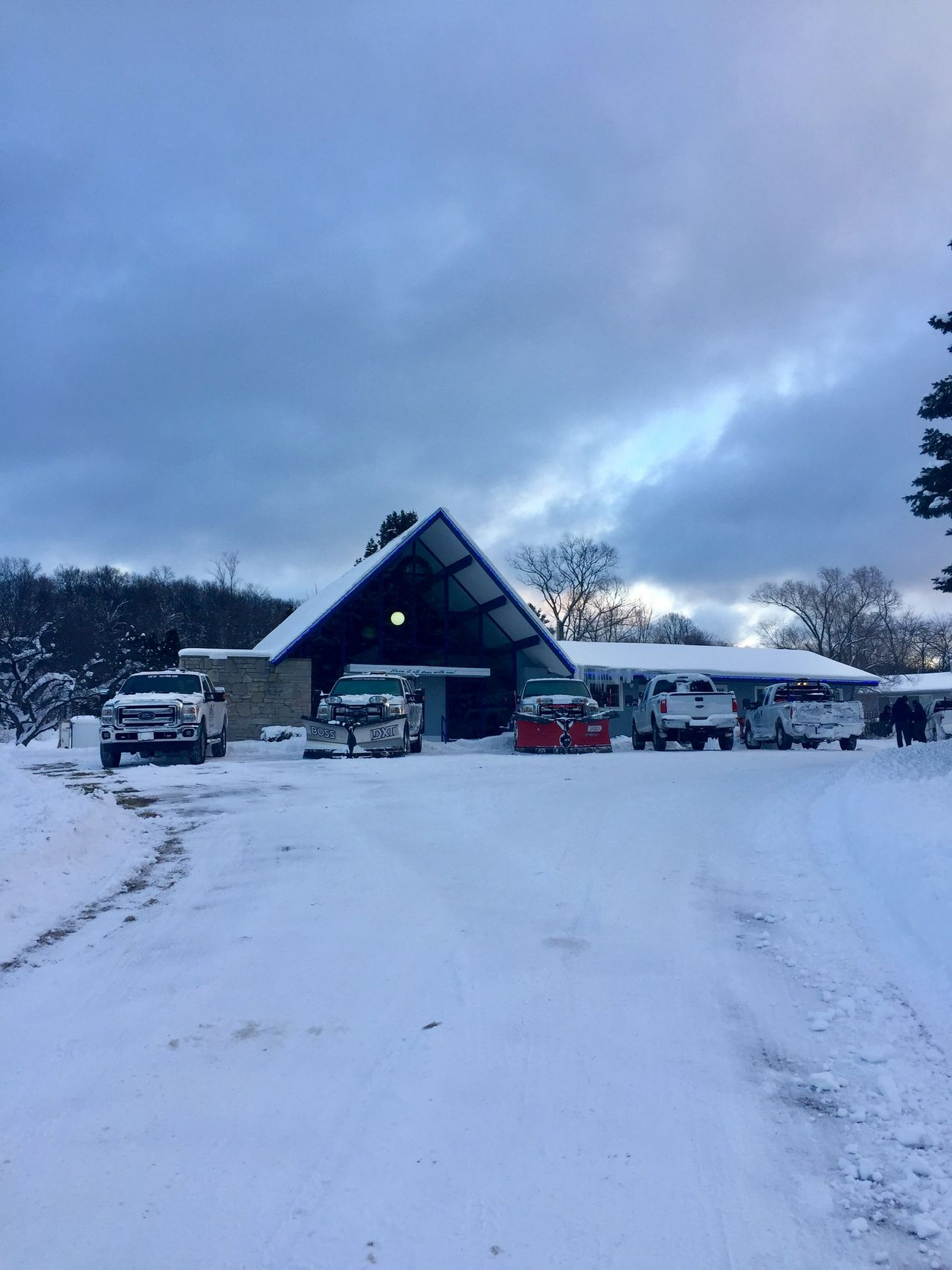 a snowy parking lot with cars parked in front of a building