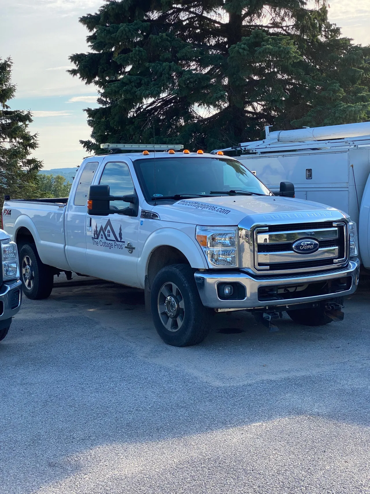 a white truck is parked next to a white van in a parking lot