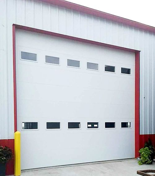A large white garage door with red trim and windows