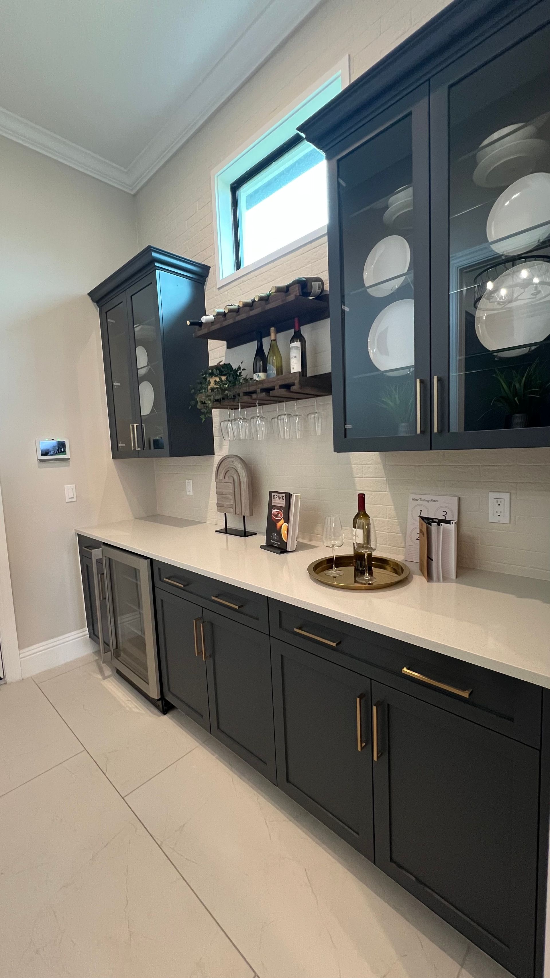 A home bar with matte black cabinets, white countertops, glass-front upper storage, open shelving, and a wine cooler.