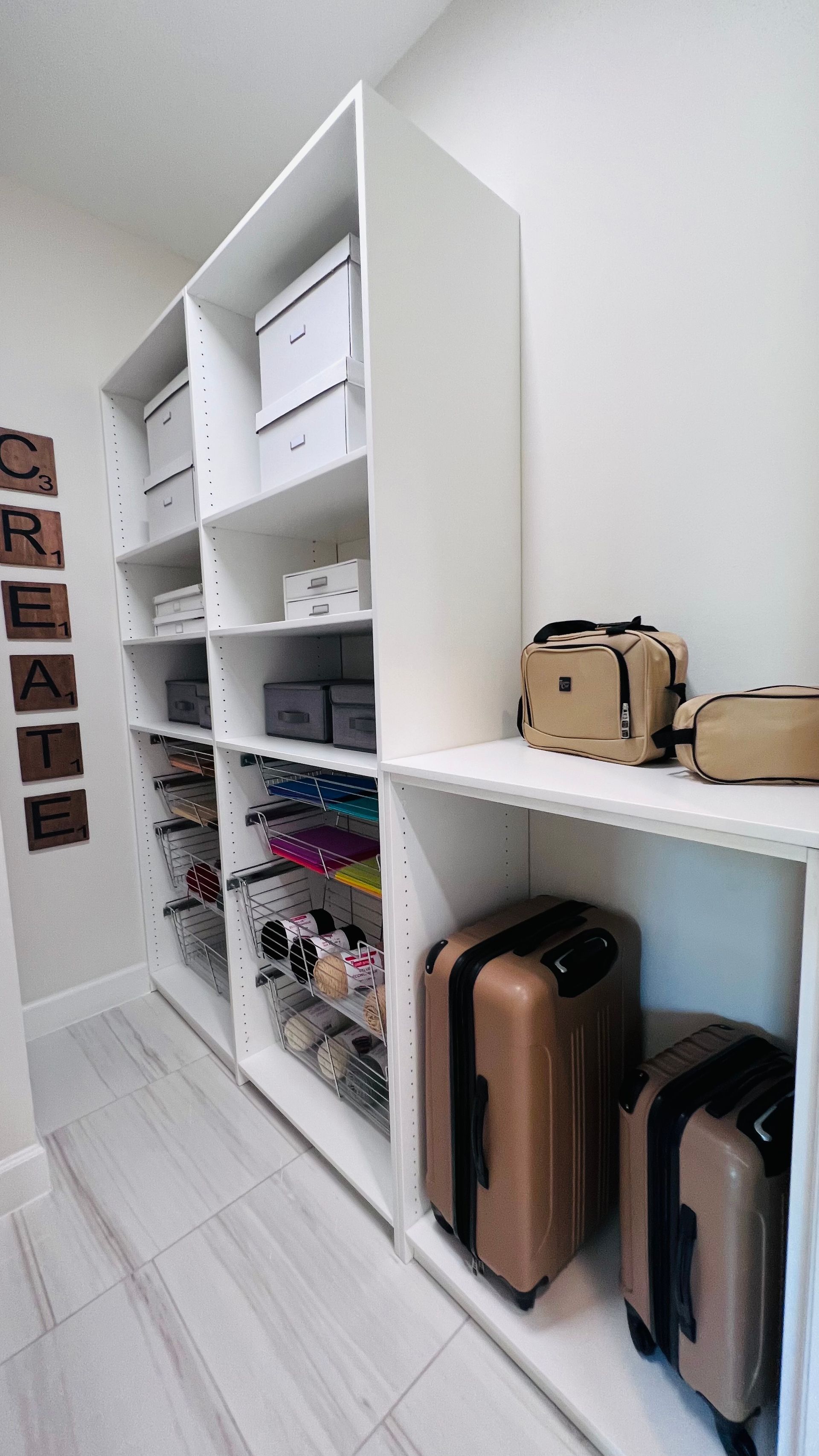 White shelving unit filled with bins, craft supplies, and organized luggage in a bright, modern storage room.