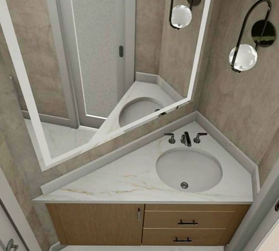 A high-angle view of a triangular corner bathroom vanity with a white marble countertop, wood cabinet, and wall mirror.