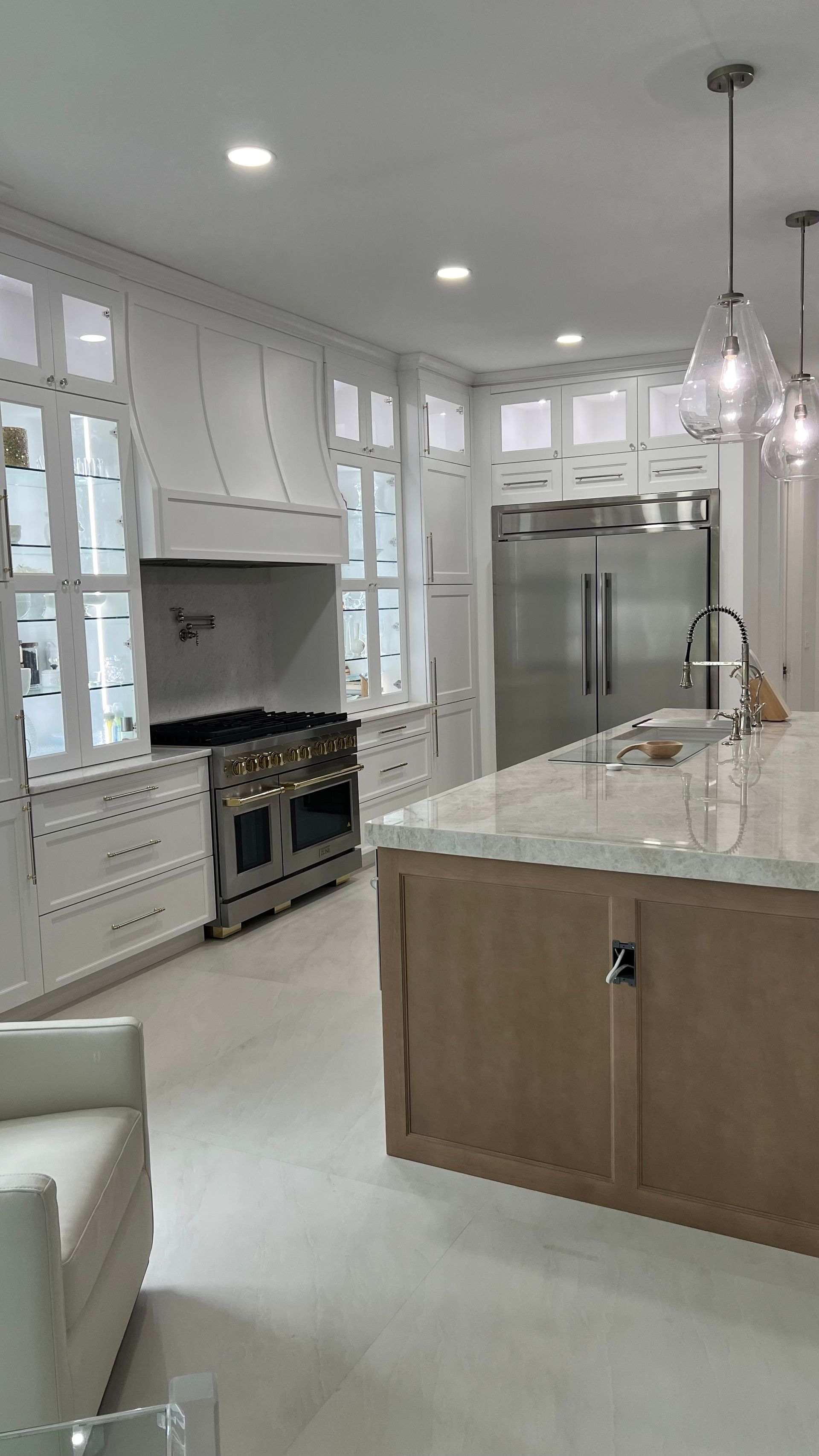 Bright, spacious kitchen with white cabinetry, a large wooden island, stainless steel appliances, and glass pendants.