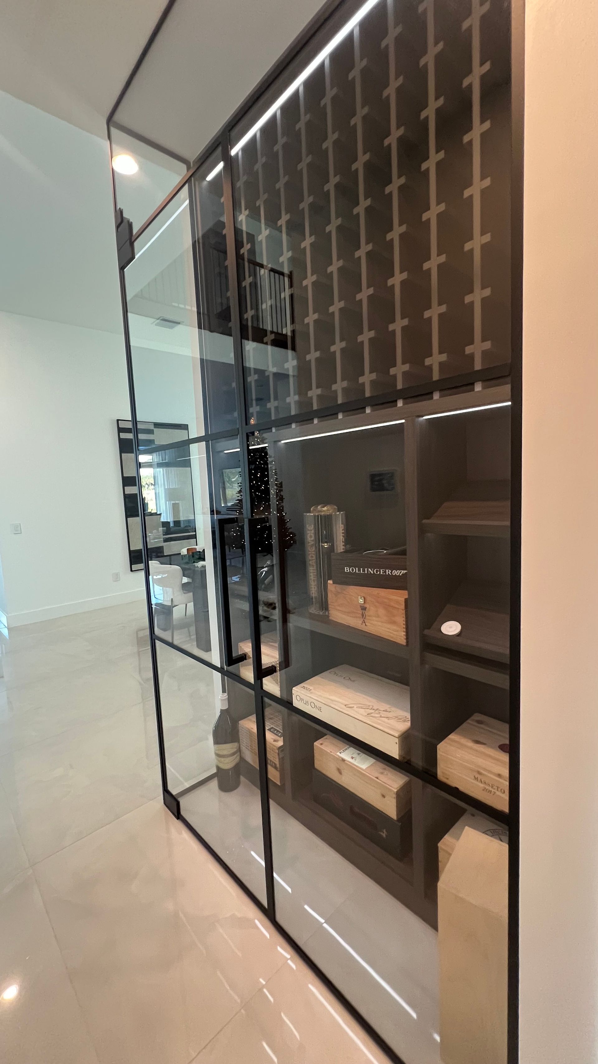 A tall, black metal cabinet with glass doors and internal lighting, displaying various decorative objects on its shelves.