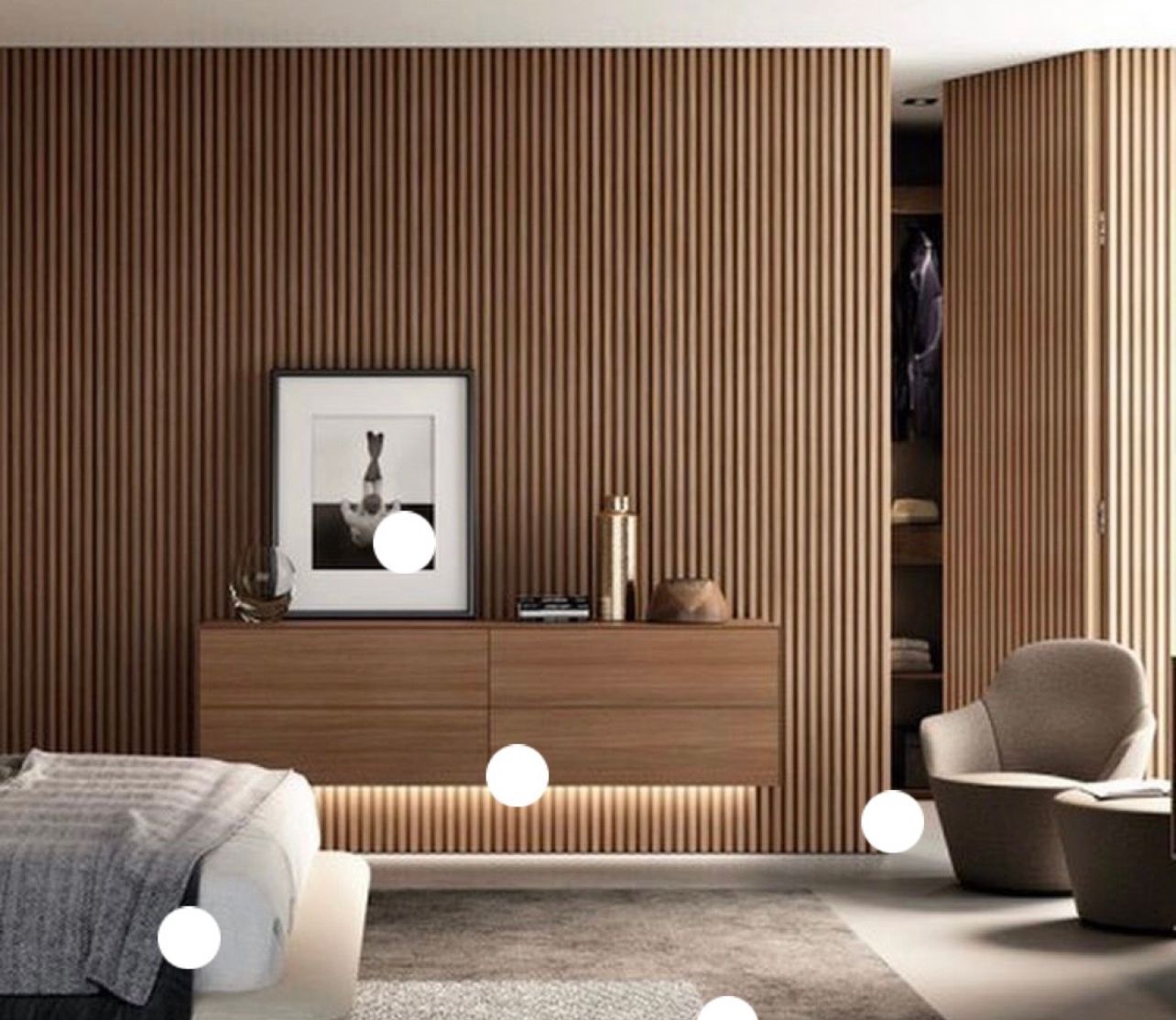 Modern bedroom with wood-slatted walls, a floating wooden cabinet with under-lighting, and a cozy armchair.