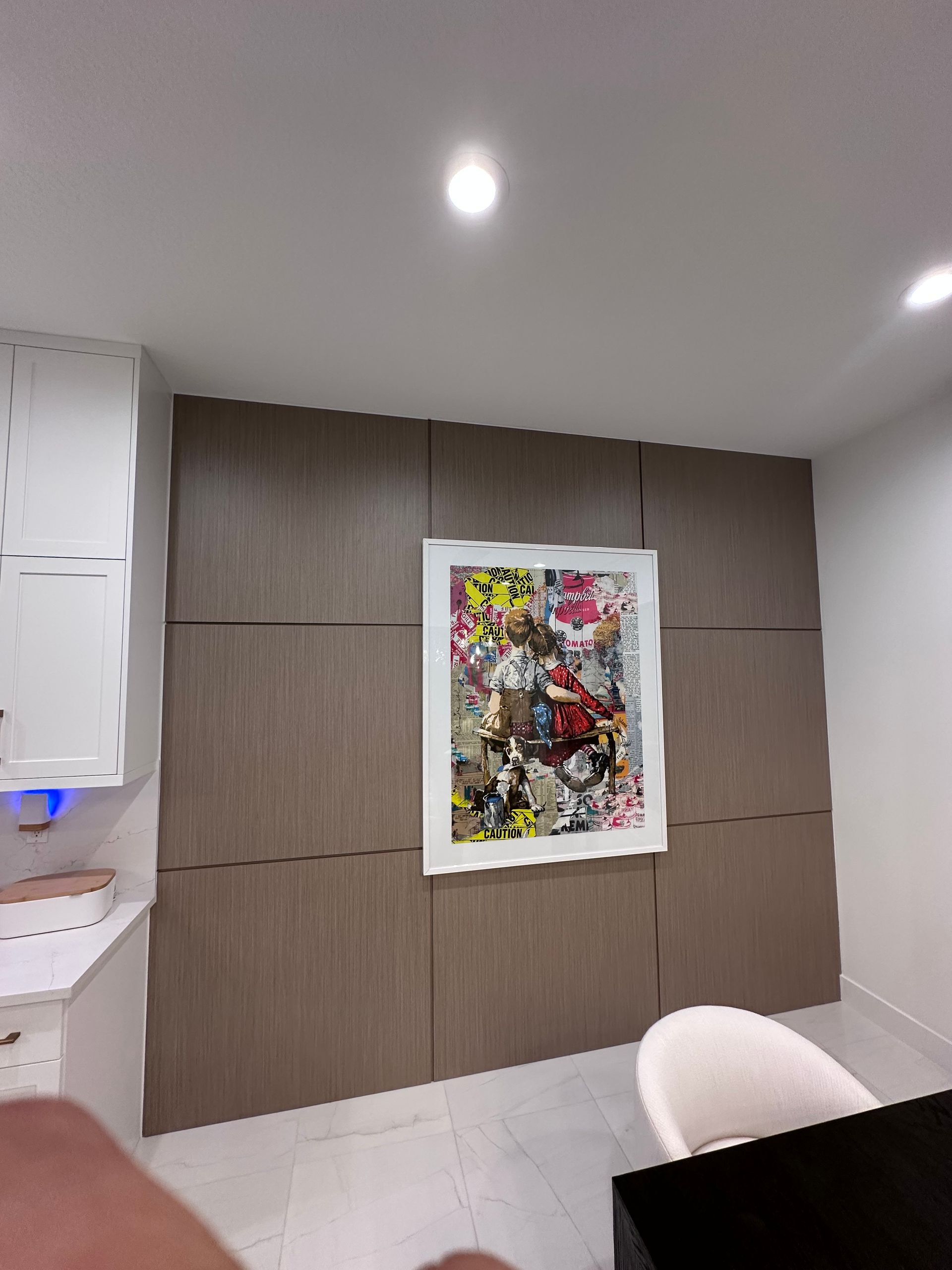 An interior view showing a wall covered in horizontal wood-grain panels with a large, vibrant, abstract art piece.