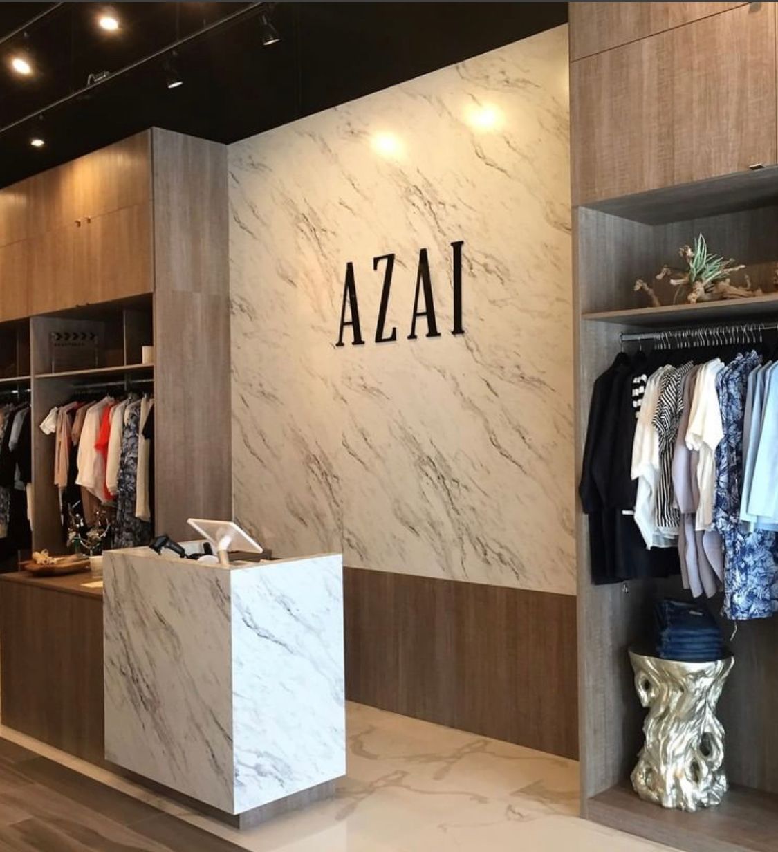 A modern clothing store interior featuring a marble-topped reception desk, a wall with the word 