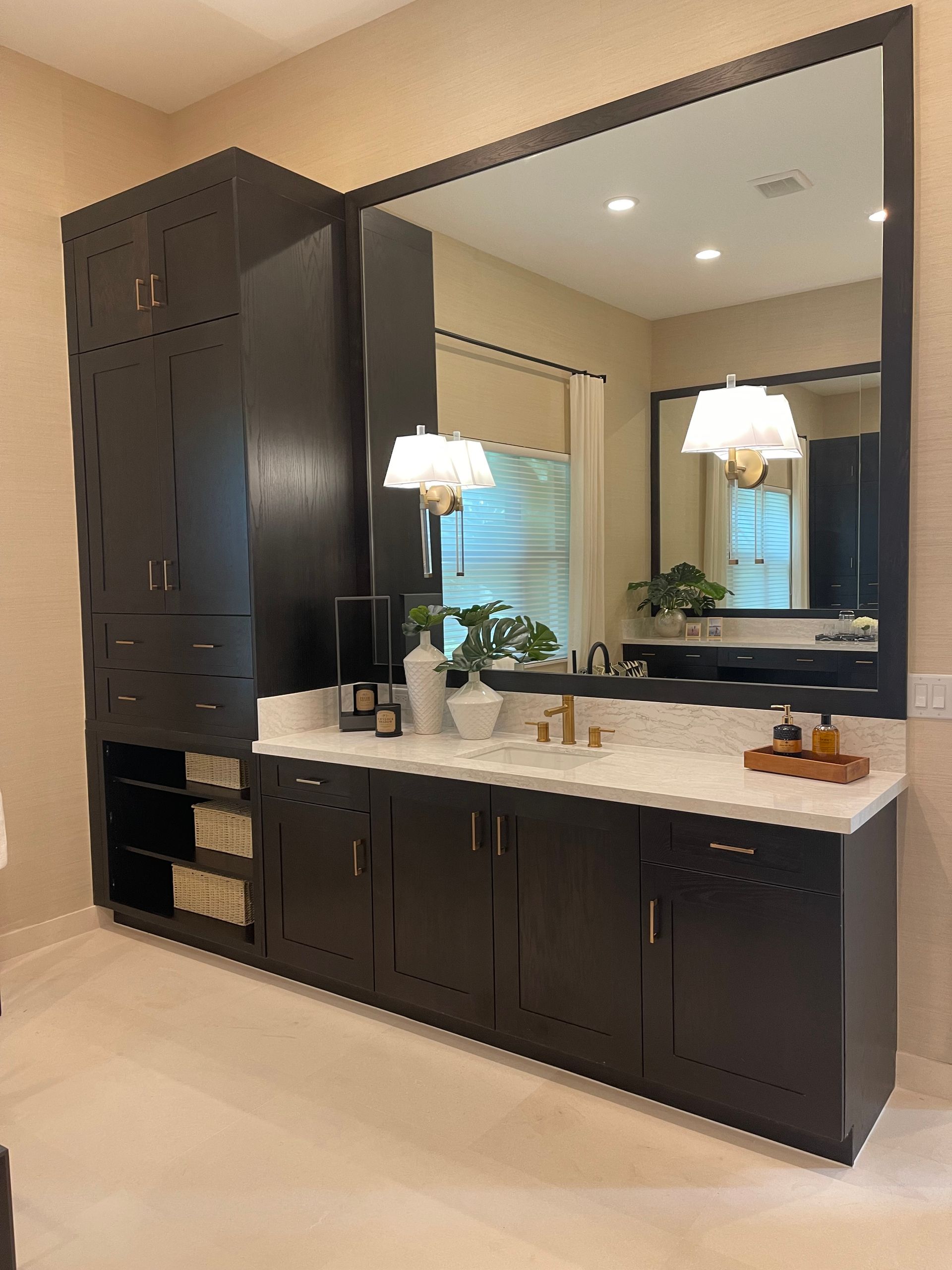 A dark wood bathroom vanity with a large mirror, white countertop, open shelving, and integrated cabinetry.